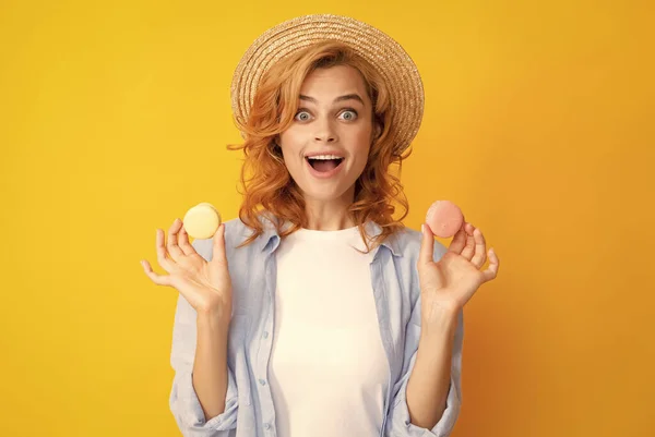 stock image Young pleased woman isolated over yellow background eating macaroons. Girl eat french macarons