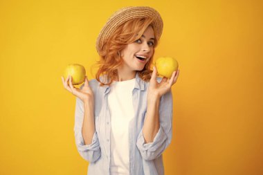 Sarı arka planda elma tutan mutlu genç kız. Elmalı güzel bir kadının portresi.