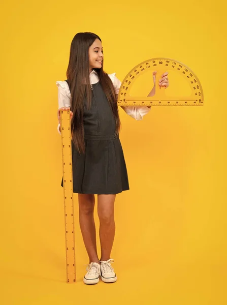 stock image Back to school. School girl hold ruler measuring isolated on yellow background. Happy girl face, positive and smiling emotions