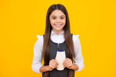 Genç kız, sarı arka planda şişe şampuanı ya da duş jeli gösteriyor. Saç kozmetik ürünü. Şişeyi hazırla.