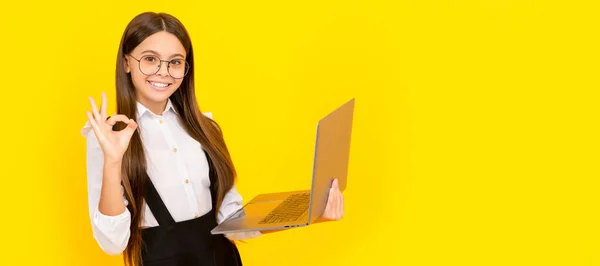 stock image happy child in school uniform and glasses study on laptop with ok gesture, e learning.