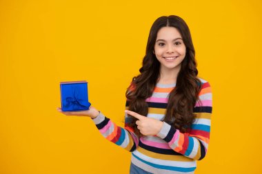 Happy teenager, positive and smiling emotions of teen girl. Child with gift present box on isolated studio background. Gifting for kids birthday