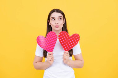 Sevgililer Günü. Ellerinde kalbi olan güzel genç bir kadın. Sarı arka planda kağıt kalpli çekici bir kadın.
