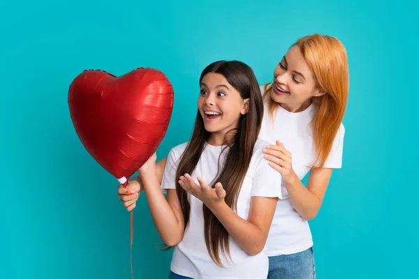 Love mom. Happy mothers day. Child daughter is congratulating mom and giving her heart balloon. Mum and child teenager girl smiling. Family holiday