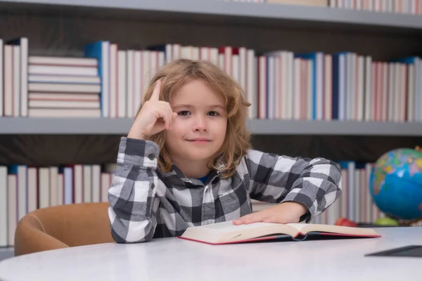 Kid reading a book in a school library. School boy education concept