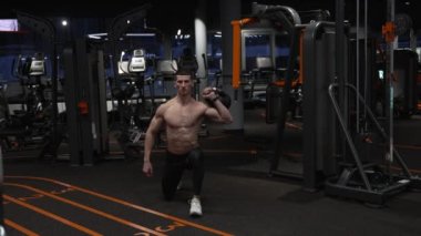 Spor salonunda kettlebell ile çömelmiş kaslı bir sporcu. Sporcu jimnastik salonunda kettlebell ile çömeliyor. Spor salonundaki spor çanlı sporcu.