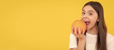 Mutlu çocuk sarı arka planda greyfurt yer, vitamin. Greyfurt portakallı çocuk portresi, yatay poster. Kopyalama alanı olan başlık