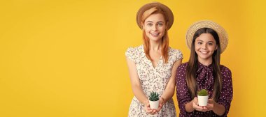 Anne ve kız çocuk afişi, kopyalama alanı, izole bir arka plan. Sarı arka planda saksı bitkisi olan neşeli bir anne ve kız.