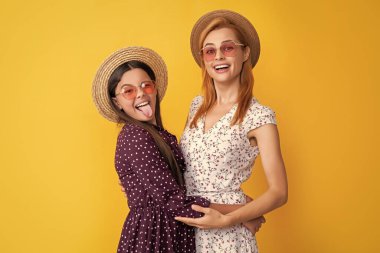 Sarı arka planda hasır şapkalı anne ve kız.