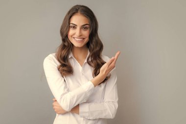 Woman point at copy space, showing copyspace pointing. Promo, girl showing advertisement content gesture, pointing with hand recommend product. Isolated grey background
