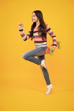 Teenagers youth casual culture. Teen girl with skateboard over isolated studio background. Teenager in fashion stylish clothes. Happy teenager, positive and smiling emotions of teen girl