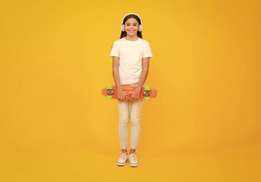 Güzel ve moda genç kız kaykayla poz veriyor. Genç sokak modası yaşam tarzı. Mutlu ergen portresi. Gülümseyen kız