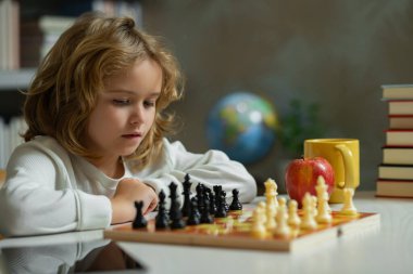 Küçük çocuk okulda satranç oynuyor. Çocuk masa oyunu oynuyor. Düşünen çocuk beyin fırtınası ve satranç fikri. Satranç okulu ve çocukların eğitim konsepti. Beyin gelişimi ve mantık