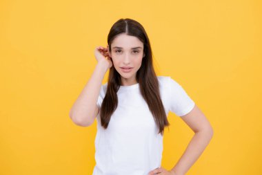 Zevkli bir kadın model tatmin edici görünüyor. Sarı arka planda izole edilmiş güzel bir kadının stüdyo portresi