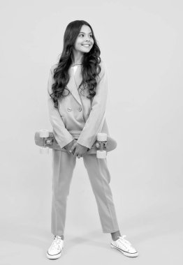 Studio shot of trendy teenage fashion model in casual look. Teenager youth hipster urban lifestyle. Child girl in street style in hipster clothes with a skateboard