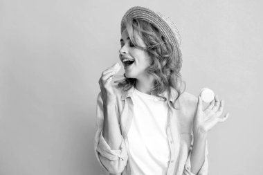 Tatlı, genç bir kadın. Kurabiye tutuyor. Güzel gülümseyen genç kız sarı arka planda renkli badem kurabiyeleri yiyor.