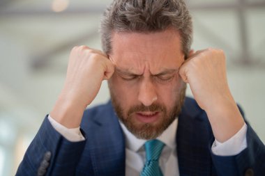 Bilgisayar çalışmalarından sonra baş ağrısı çeken yorgun bir adam. Kafaya dokunmaktan yorgun düşmüş, baş ağrısını dindirmiş, migren olmuş. İş sorunları. İflas, mali sorun ve kriz kavramı