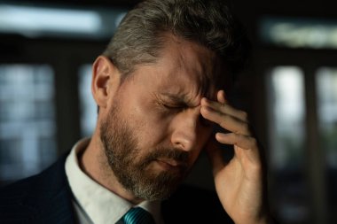 Yorgun adamın korkunç bir baş ağrısı var. Bitkin, sağlıksız hisseden, baş ağrısı hastalığına üzülen bir adam. Stresli orta yaşlı adamın başı ağrıyor. Migren ve baş ağrısı konsepti