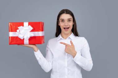 Portrait of a happy girl with gift box isolated over gray background. Woman holding gift present