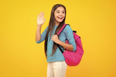 Happy teenager portrait. Schoolgirl in school uniform with backpack. Teenage girl student on yellow isolated background. Learning and education children. Smiling girl