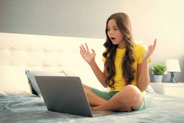 Genç liseli kız evde dizüstü bilgisayarla ders çalışıyor. Şaşırmış yüz, şaşırmış genç kız duyguları.