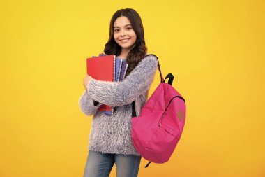 Schoolchild, teenage student girl hold book on yellow isolated studio background. School and education concept. Back to school. Happy teenager, positive and smiling emotions of teen girl