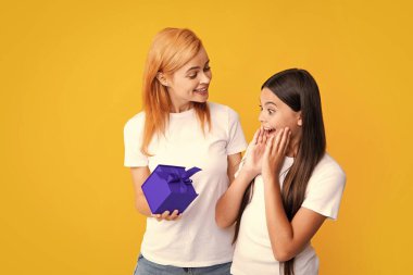 Mother gives a gift to her teen daughter, isolated background. Happy family concept. Girl with mother together. Valentine