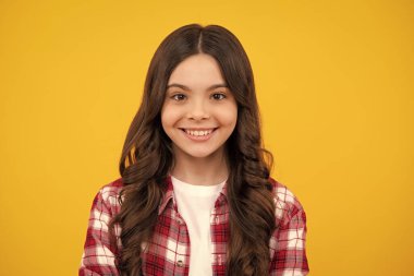 Mutlu ergen, pozitif ve gülümseyen genç kız duyguları. Kafkasyalı genç kızın yakın portresi. Sarı izole edilmiş stüdyo arka planında sevimli bir gencin fotoğrafı.
