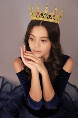 Teenager princess child celebrates success win and victory. Teen girl in queen crown isolated on grey background