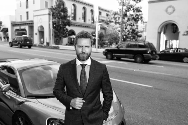 handsome man in expensive suit. confident business executive rent car. boss stand by luxury automobile. successful dealer. dealership. car insurance. businessman near auto outdoor.