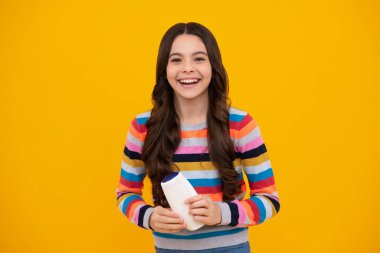 Şampuan kremi kullanan bir çocuk. Günlük kozmetik bakım. 12, 13, 14 yaşlarındaki ergen çocuğun elinde saç ve cilt bakımı şişesi var. Güzellik sağlığı ve kozmetik ürünleri. Mutlu genç