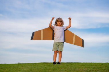Başarı ve çocuk lider konsepti. Kağıt kanatlı ya da oyuncak uçaklı çocuk pilot yazın doğada seyahat etmeyi hayal eder.