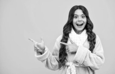 Onun yakın plan portresi. Güzel, çekici, neşeli, şaşkın kız, sarı arka planda izole edilmiş fotokopi alanını işaret ediyor. Kopyalama alanını düzenle