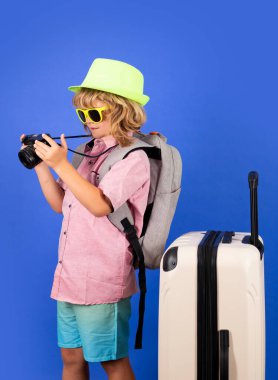 Traveler tourist kid boy 7-8 years old on isolated studio background. Travel on weekends getaway. Independent kid boy with big travel bag