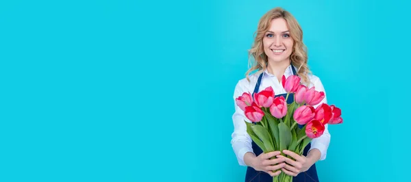 Genç Bir Kadın Mavi Arka Planda Bahar Lale Çiçekleriyle Önlükle — Stok fotoğraf