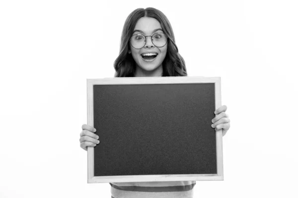 stock image Teenager child holding blank chalkboard for message Isolated on a white studio background. Empty text blackboard, copy space mock up. Happy girl face, positive and smiling emotions