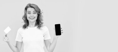 Heyecanlı genç bayan cep telefonu kredi kartı kullanarak aşırı sarı arka planı izole etti. İzole edilmiş yüz portresi, taklit alanı olan pankart