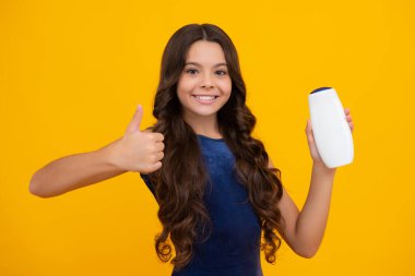 Şampuan kremi kullanan bir çocuk. Günlük kozmetik bakım. 12, 13, 14 yaşlarındaki ergen çocuğun elinde saç ve cilt bakımı şişesi var. Güzellik sağlığı ve kozmetik ürünleri. Mutlu kız yüzü, pozitif ve gülümseyen duygular