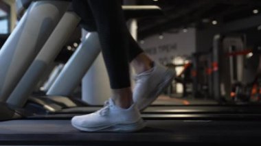 Spor salonunda spor ayakkabıları koşu bandında yürüyor. Koşu bandı egzersizi. Beden eğitimi için spor aletleri. Fitness ve kardiyo eğitimi. Spor eğlencesi..