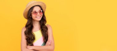 Yazın hasır şapkalı ve gözlüklü mutlu çocuk sarı arka planda kıvırcık saçlı, yaz mevsiminde. Çocuk yüzü, yatay poster, izole edilmiş genç kız portresi, fotokopi alanı olan pankart