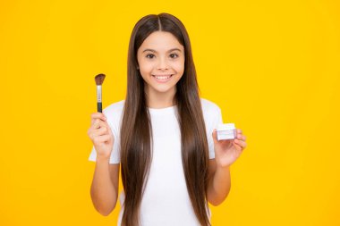 Güzellik, makyaj ve çocukların makyaj malzemeleri. 12, 13, 14 yaşlarında genç bir kız. Yüzüne allık sürmüş. Arkaplanda izole edilmiş. Mutlu ergen portresi. Gülümseyen kız