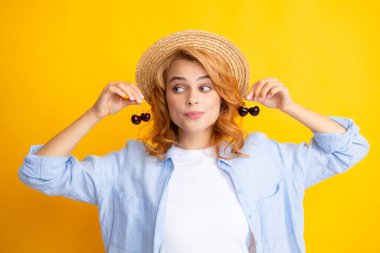 Portrait of woman with cherries on yellow studio isolated background