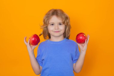 Kids face with fruits. Kid with apple in studio. Studio portrait of cute child hold apple isolated on yellow background