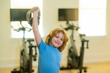 Kettlebell 'le egzersiz yapan sevimli küçük çocuk. Dambılı spor çocuk portresi. Beden eğitiminde çocuk çalıştıran çocuk. Egzersiz yapan mutlu çocuk. Sağlıklı aktiviteler, çocuk yaşam tarzı