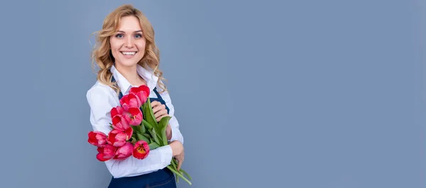 Gri Arka Planda Bahar Lale Çiçekleri Olan Önlüklü Mutlu Kız — Stok fotoğraf