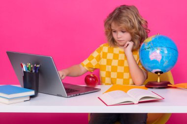 Dizüstü bilgisayar kullanan okul çocuğu. Kitabı olan 7-8 yaşındaki okul çocuğu okula geri dön. Küçük öğrenci