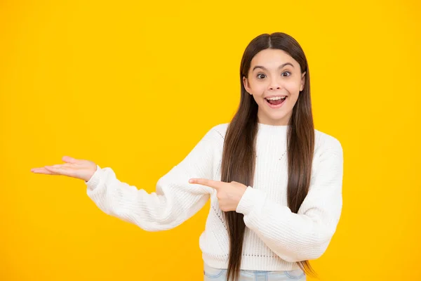 stock image Portrait of cute teenager child girl pointing hand showing adverts with copy space over yellow background