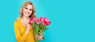 Bahar lalesi çiçekli kız. Mavi arka planda bahar çiçekleri olan mutlu genç bir kadın. İzole edilmiş yüz portresi, taklit alanı olan pankart