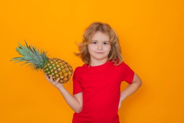 Summer fruits. Kid with pineapple in studio. Studio portrait of cute child hold pineapple isolated on yellow background