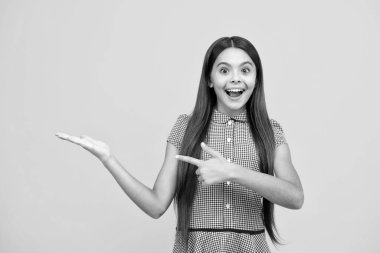 Wow, its unbelievable. Shocked teenager child pointing aside at copy space. Teen girl pointing with two hands and fingers to the side